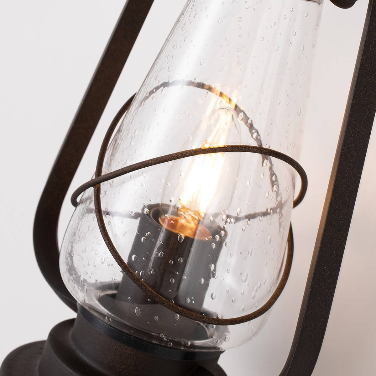 Gros plan sur le verre gouttelé, l'anneau métallique et l'ampoule à filament allumée.