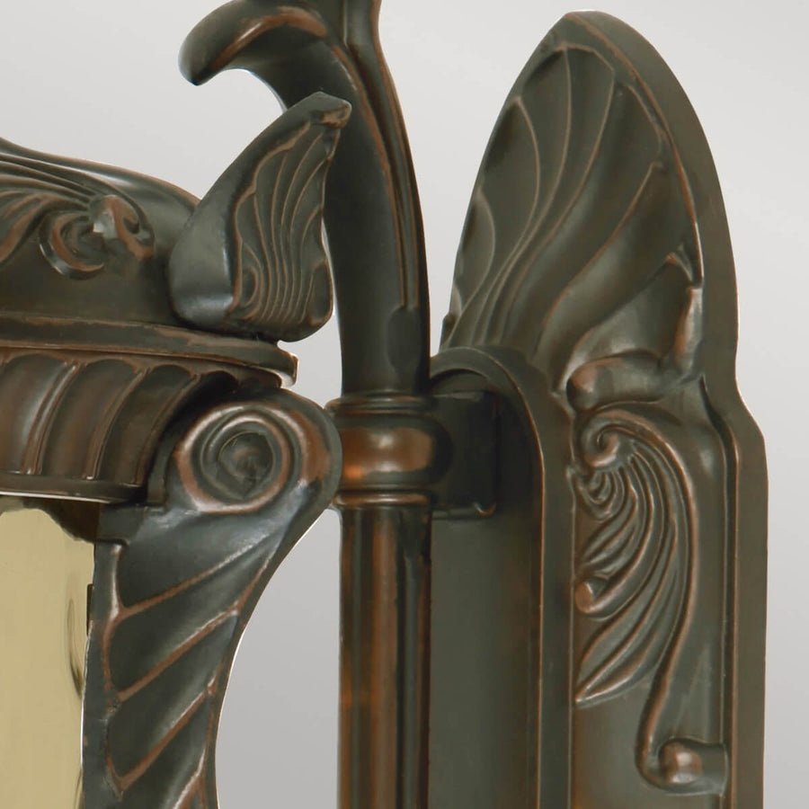 Détail du support mural orné de volutes et du raccord en bronze.