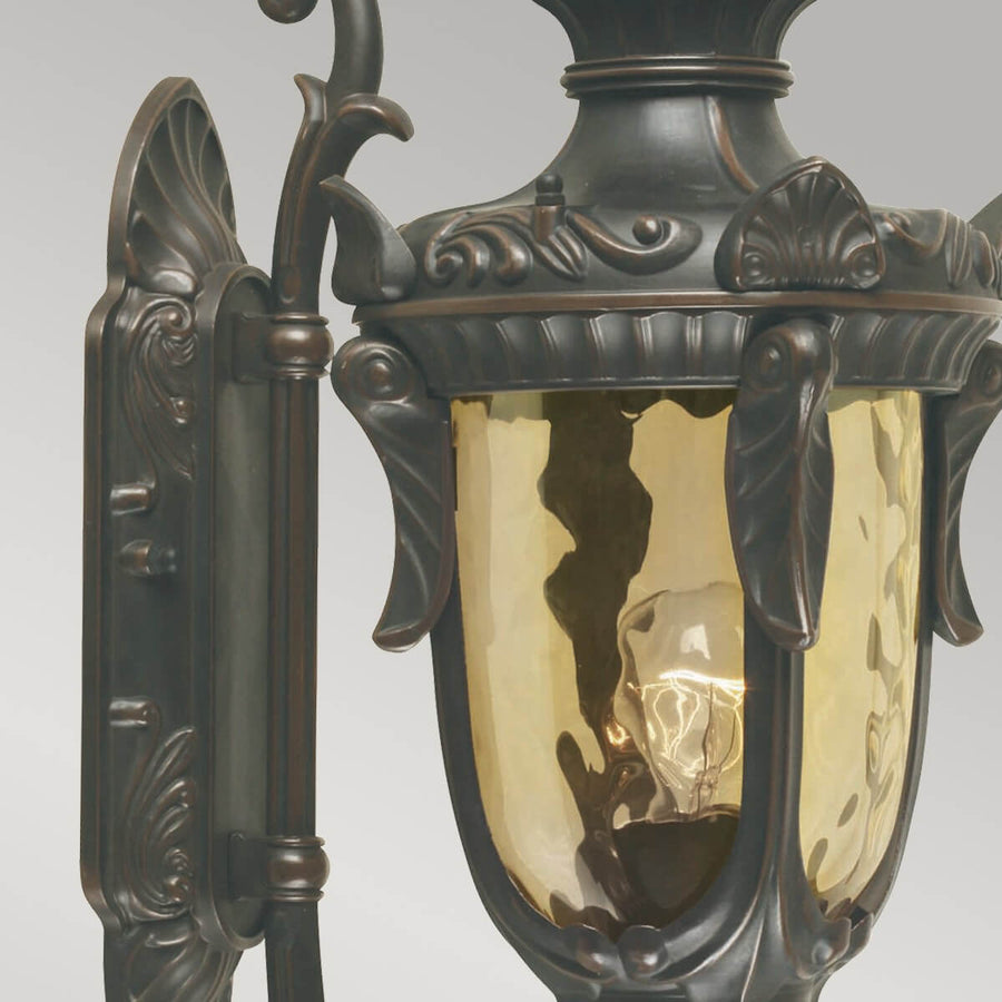 Détail du verre ambré martelé et de la platine murale ornée de volutes