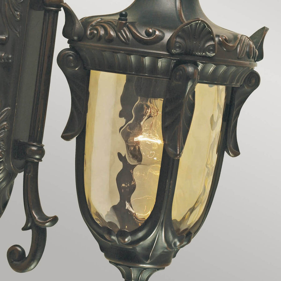 Gros plan de la lanterne, verre bombé ambré et montants décoratifs en bronze