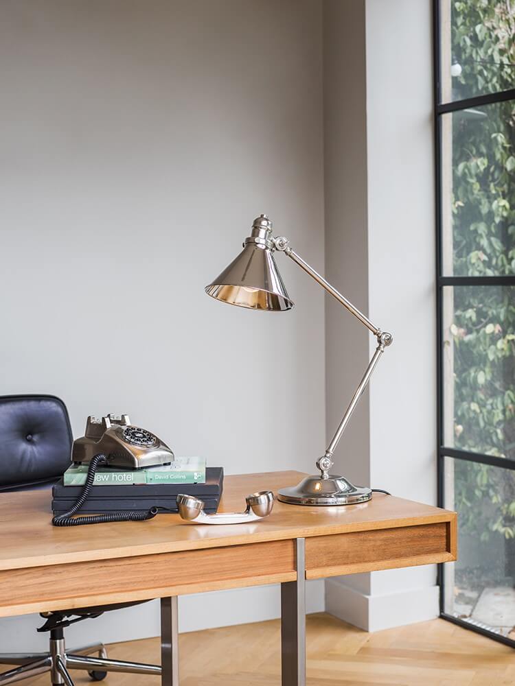 Lampe posée sur un bureau en bois dans un intérieur lumineux avec téléphone rétro.