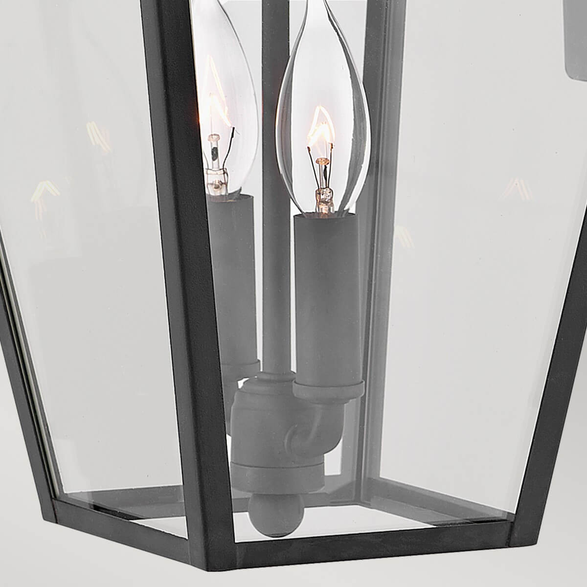 Gros plan sur les deux ampoules candélabres allumées derrière le verre