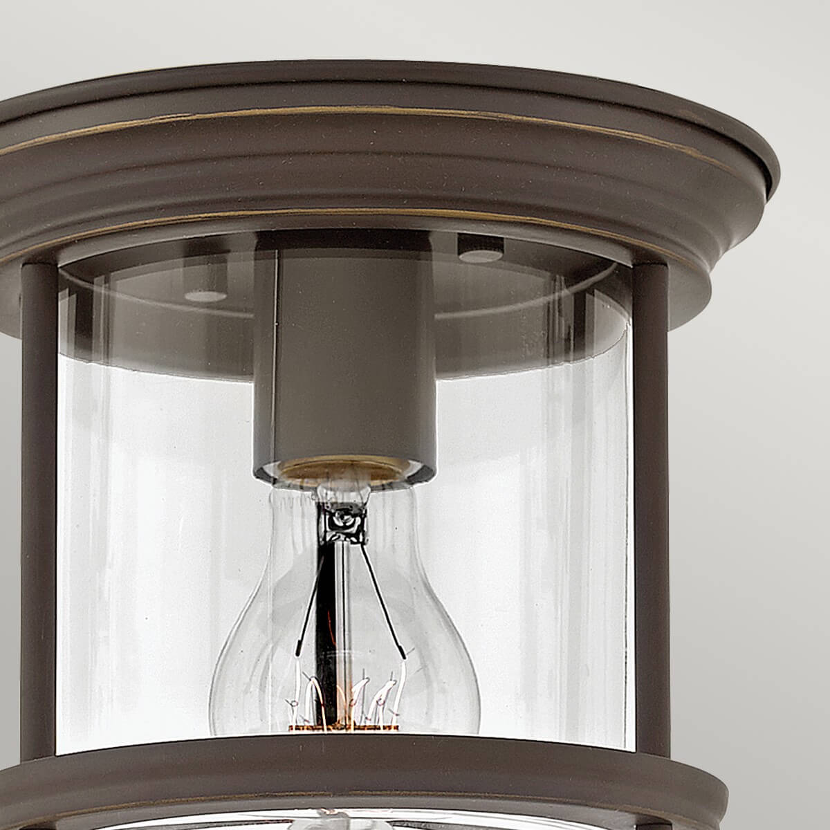 Détail du haut du luminaire : cerclage bronze et verre cylindrique transparent