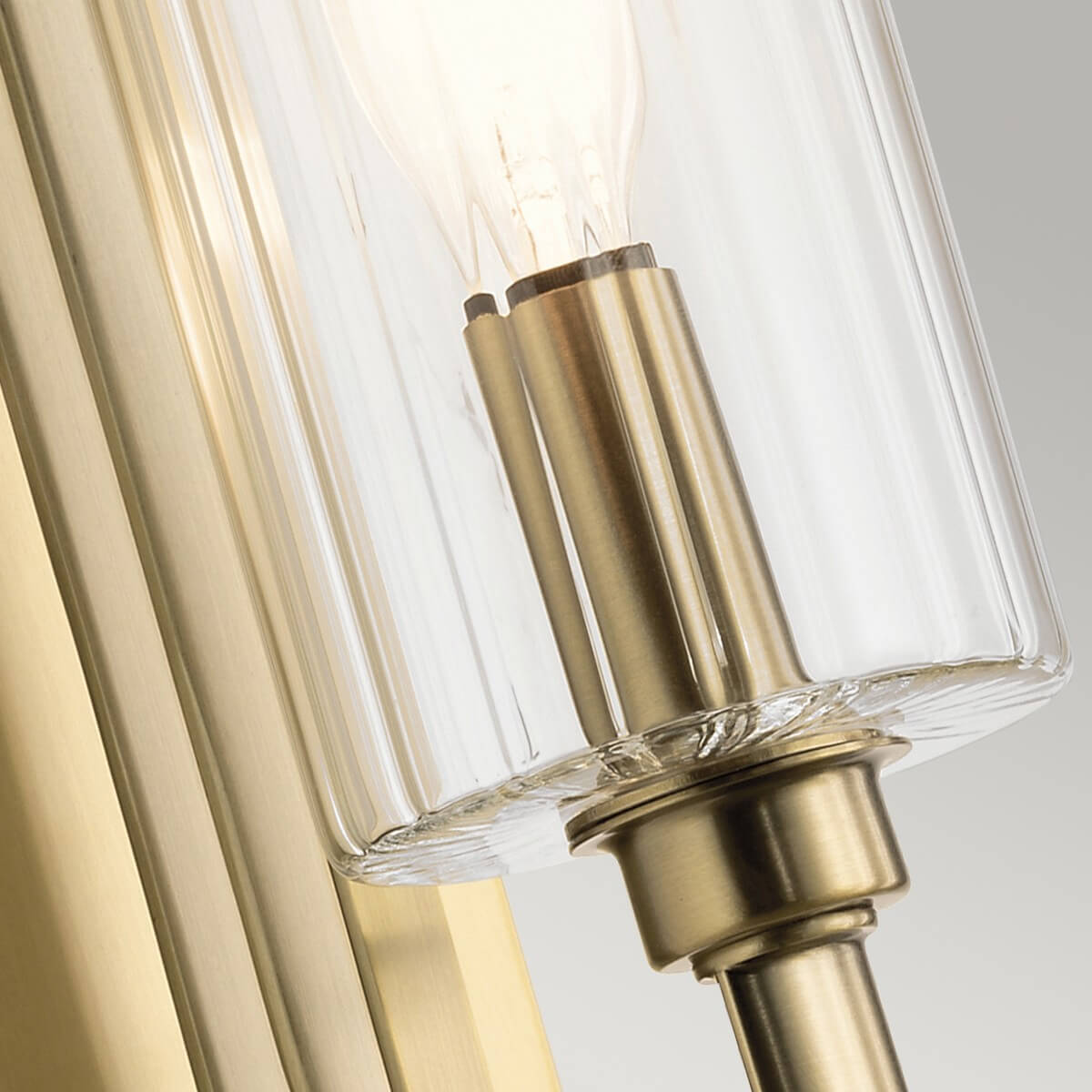 Gros plan sur la douille en laiton et le verre cylindrique avec ampoule allumée.