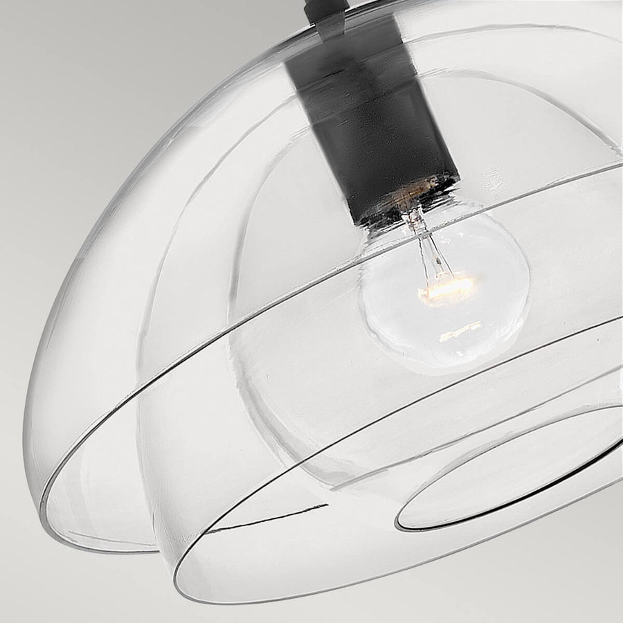 Gros plan sur l'abat-jour en verre transparent et l'ampoule allumée à l'intérieur.