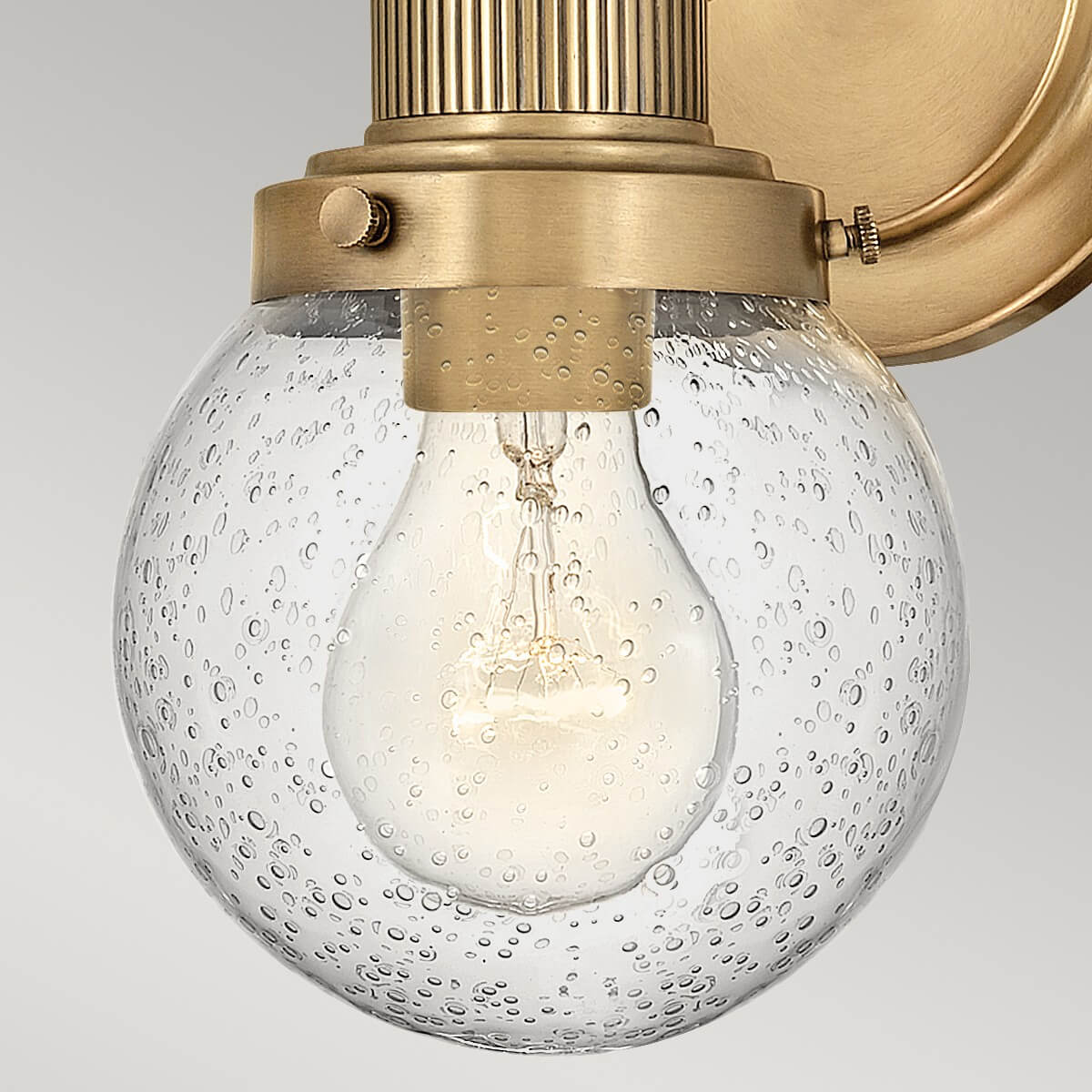 Gros plan du globe en verre bullé avec ampoule à filament allumée à l'intérieur