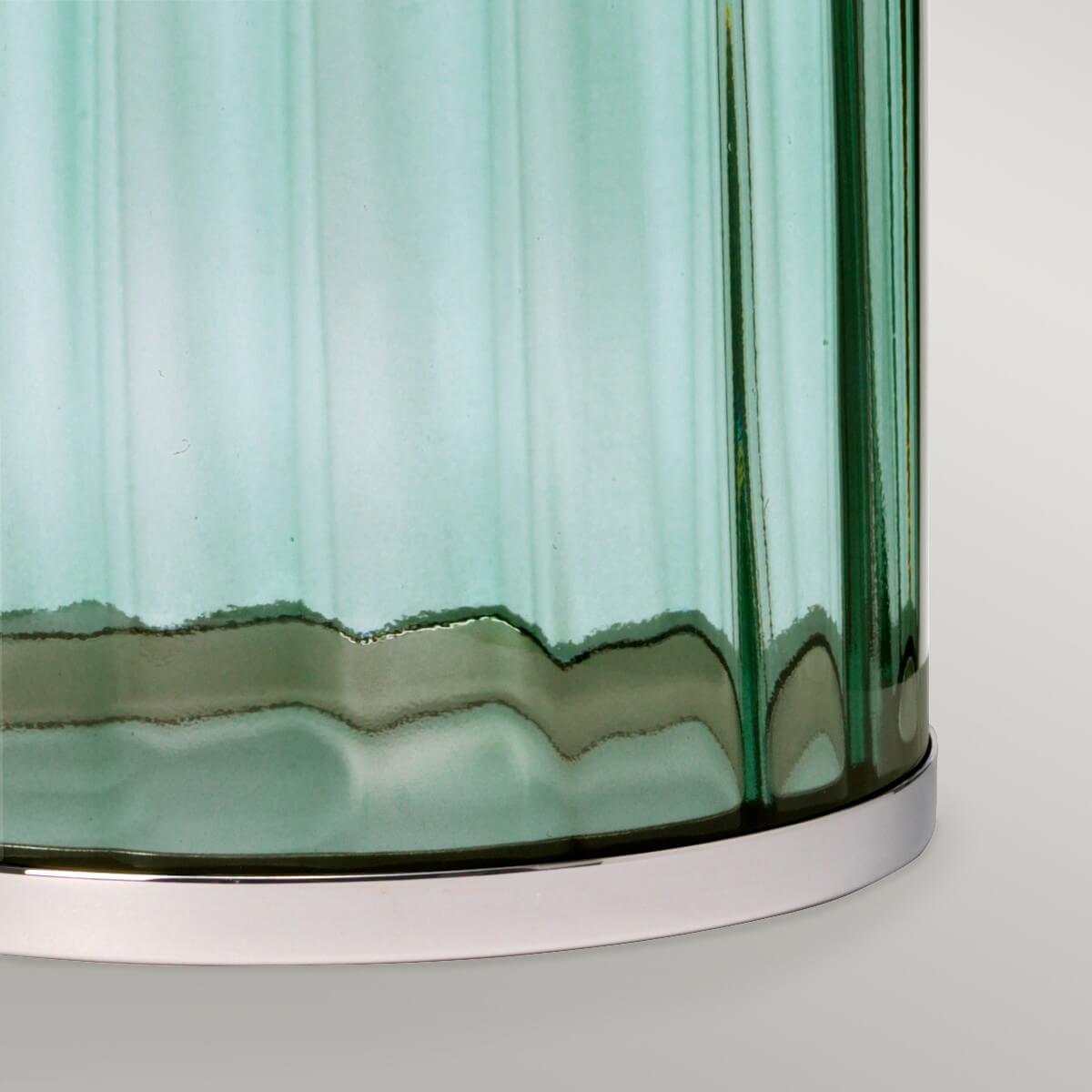 Détail du bas de la base en verre vert avec rebord ondulé et socle nickel poli.