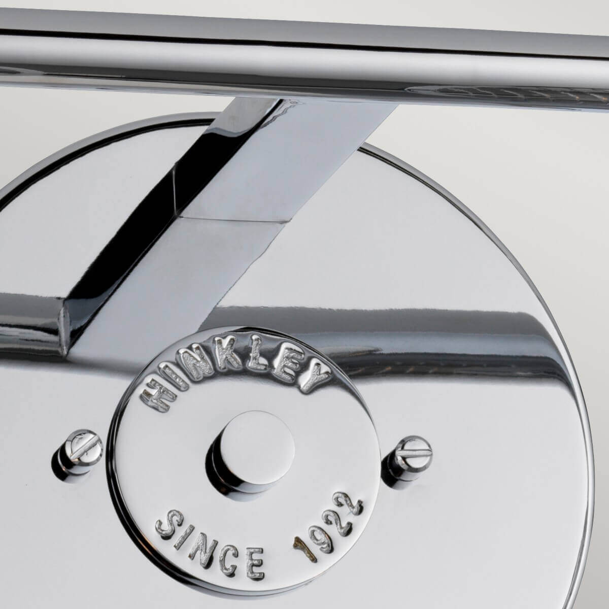 Détail de la platine murale ronde et du bras chromé avec vis de fixation