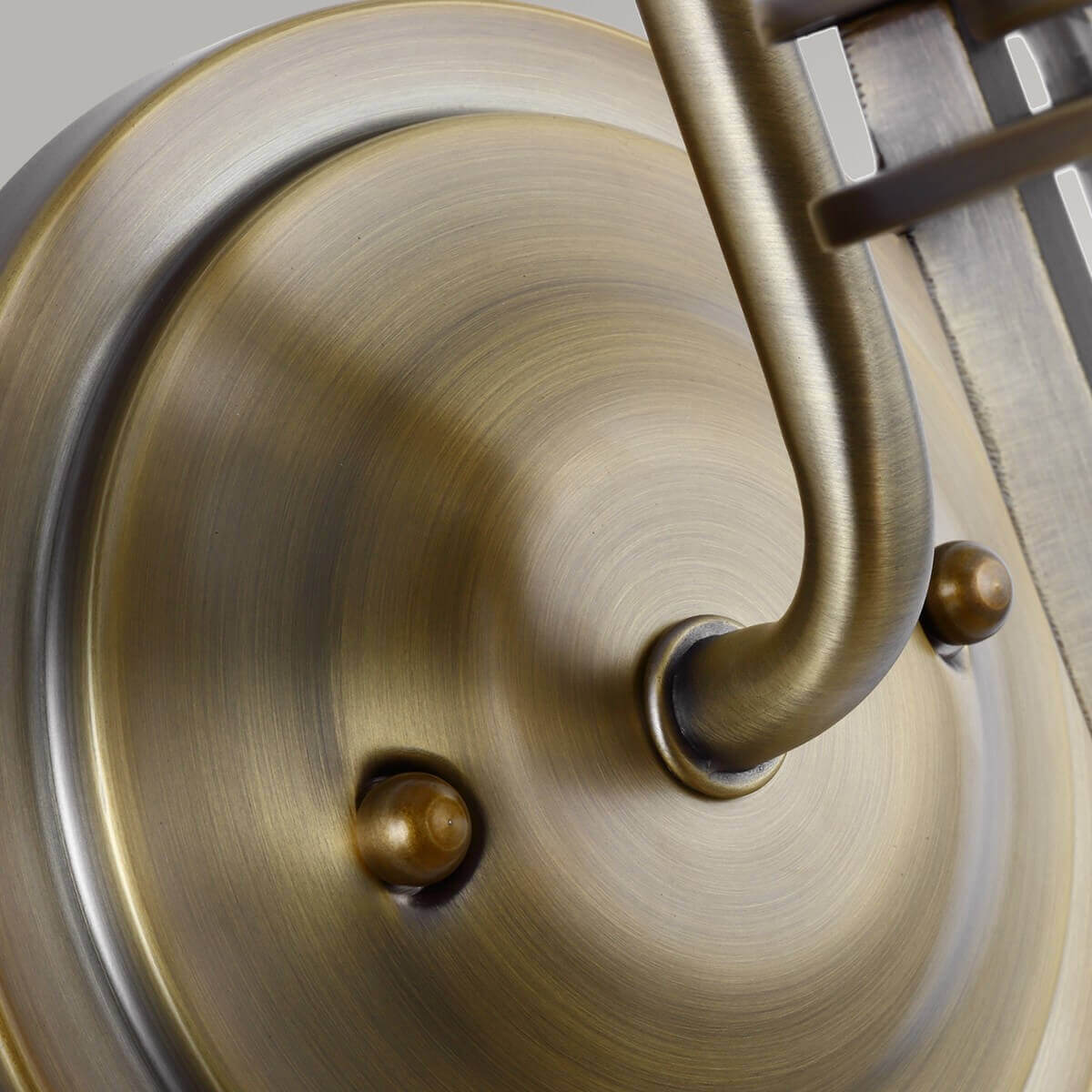 Détail de la platine ronde en laiton brossé et de ses vis de fixation.