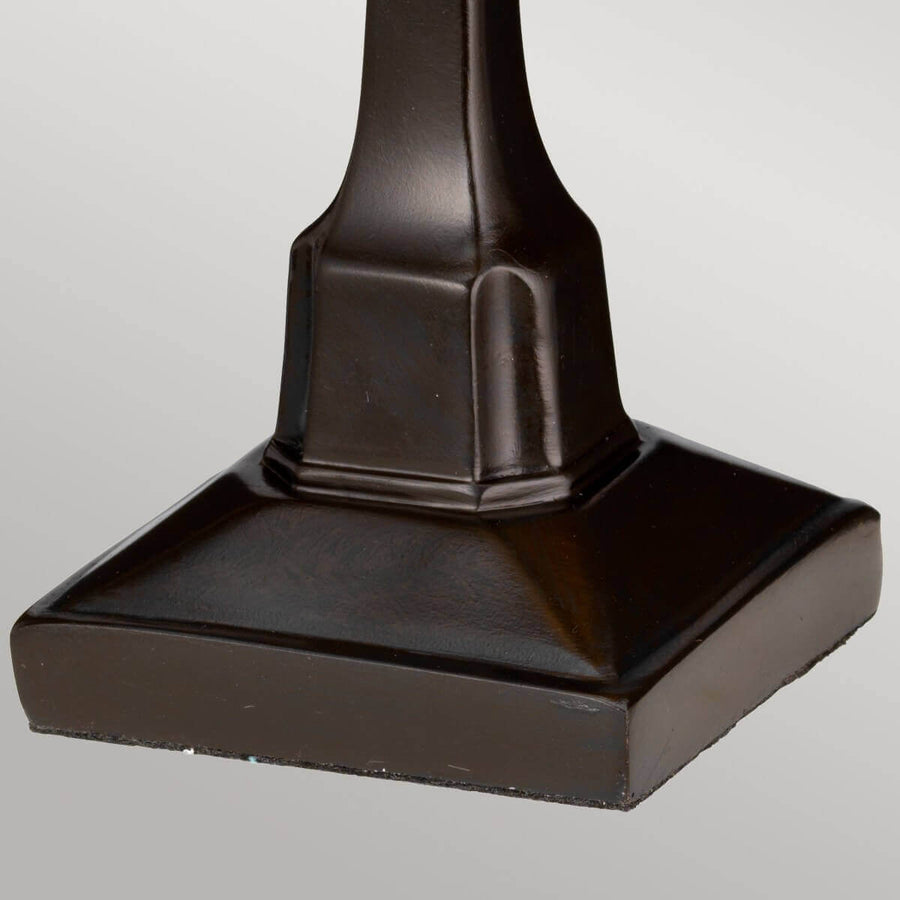 Détail du socle carré en métal bronze de la lampe à poser.