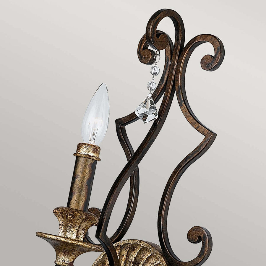 Gros plan sur la bougie et la pampille en cristal, finition bronze vieilli et volutes.