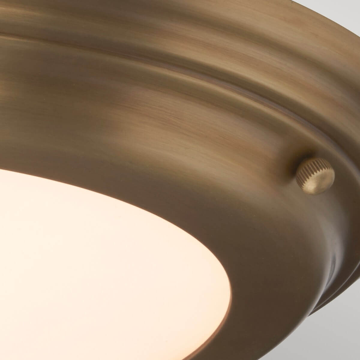 Gros plan sur la vis moletée et le bord arrondi du luminaire.