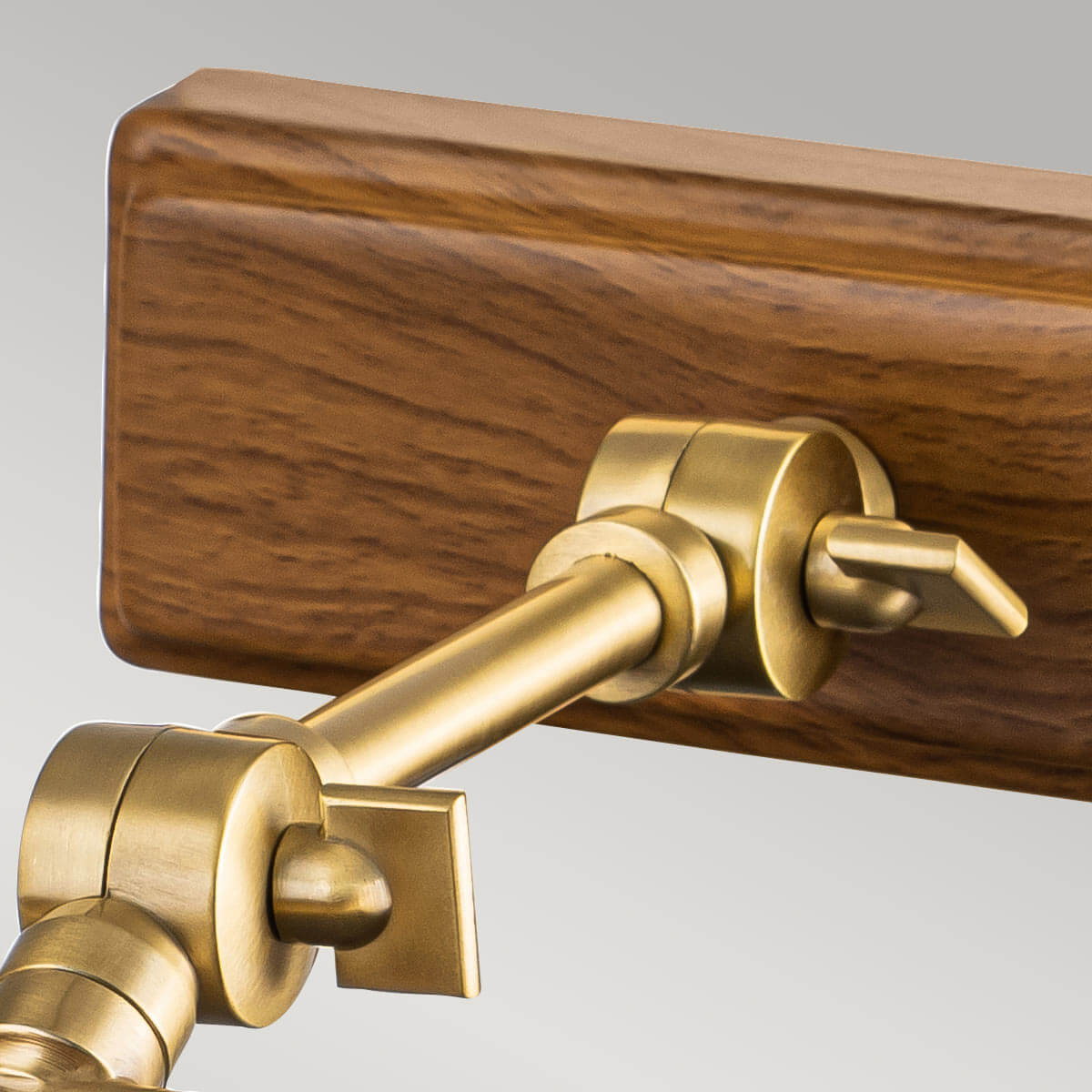 Détail du bras articulé en laiton fixé sur la platine rectangulaire en bois