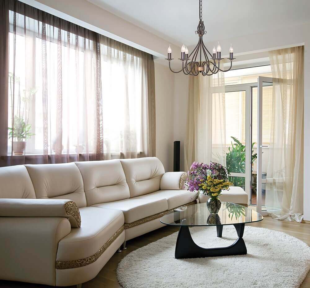 Lustre suspendu au-dessus d'un salon clair, canapé beige et table basse en verre