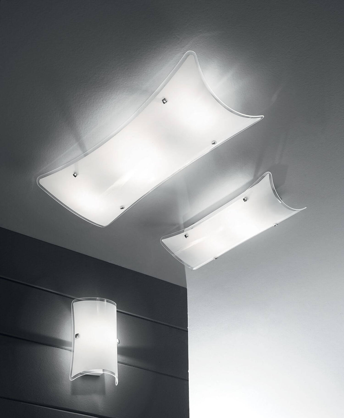 Ambiance avec luminaires blancs incurvés : deux plafonniers et une applique murale.
