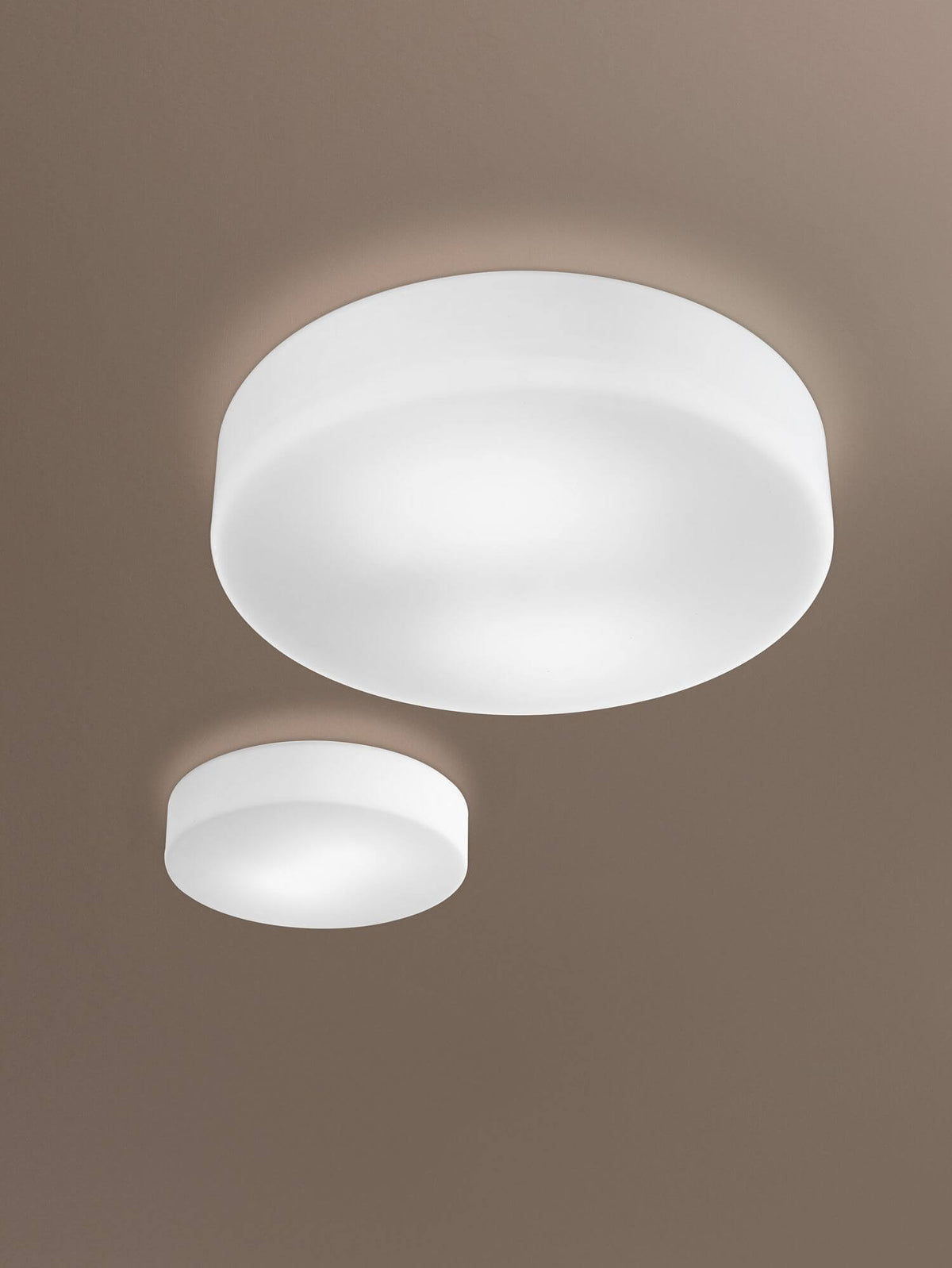 Deux tailles du plafonnier allumé, fixées au plafond dans une pièce beige