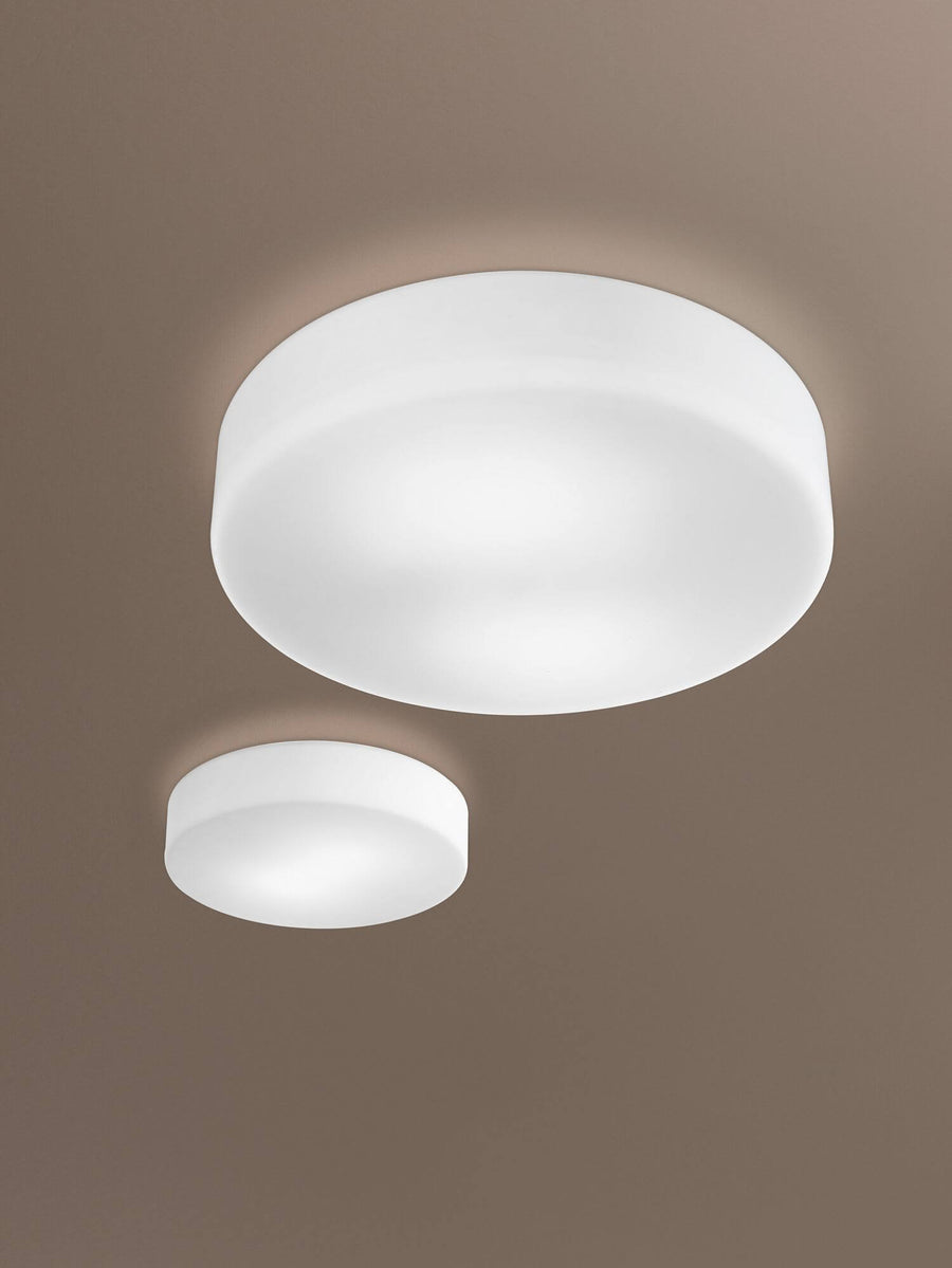 Deux tailles du plafonnier allumé, fixées au plafond dans une pièce beige