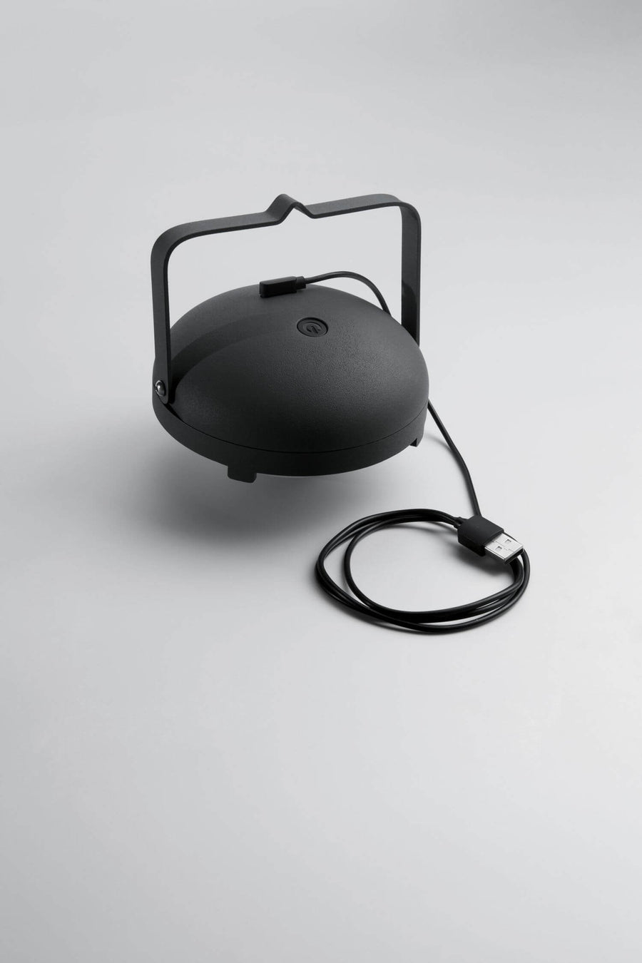 Détail du câble USB branché sous le capot noir de la lampe portable.