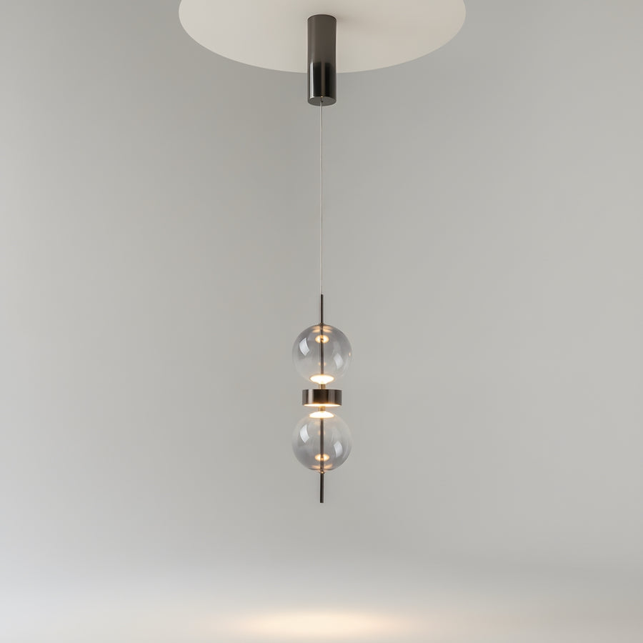 Suspension installee au plafond, ses deux globes de verre diffusent une lumiere chaude