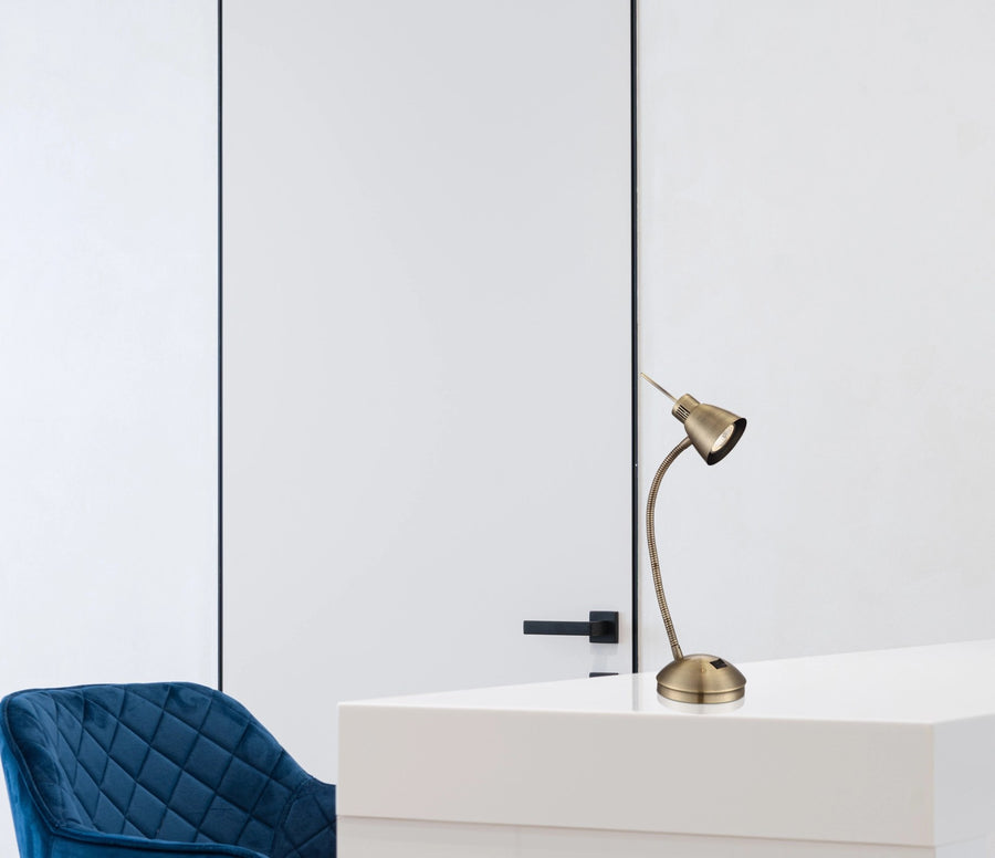 Lampe posée sur un meuble blanc dans un intérieur épuré avec une chaise bleue.