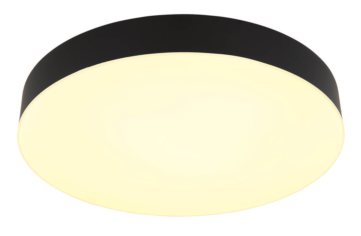 Plafonnier éclairé en lumière chaude, halo jaune doux sur la coupole blanche