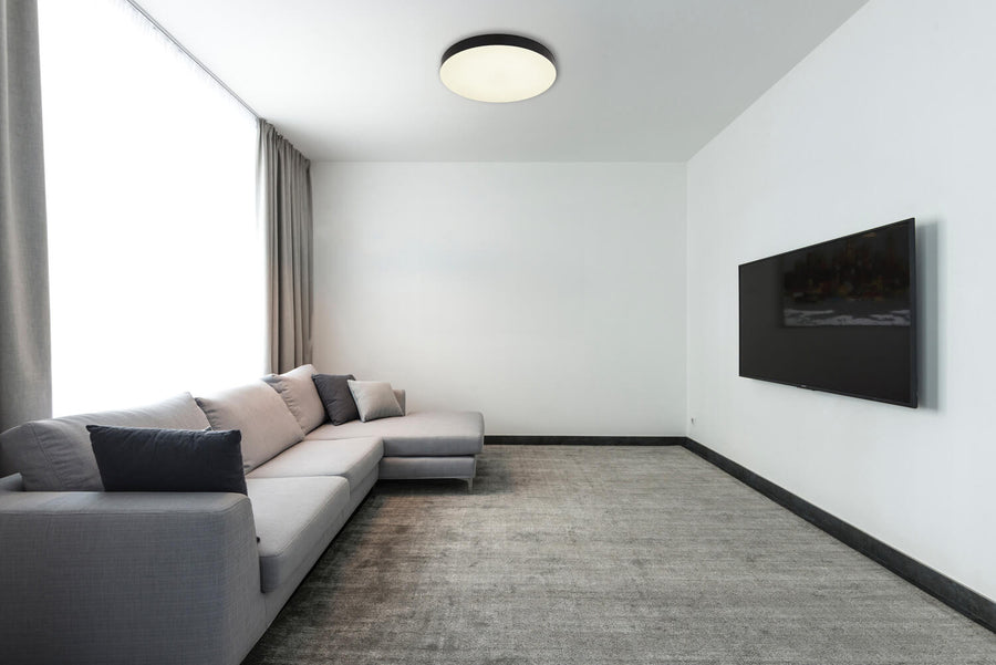 Plafonnier installé au plafond d'un salon blanc avec canapé gris et télévision murale
