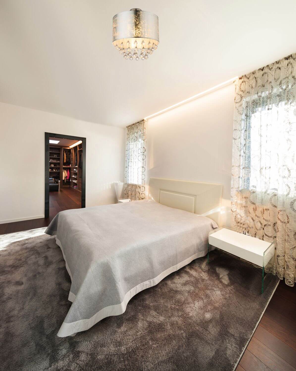 Vue du plafonnier allumé dans une chambre contemporaine au-dessus d'un lit gris