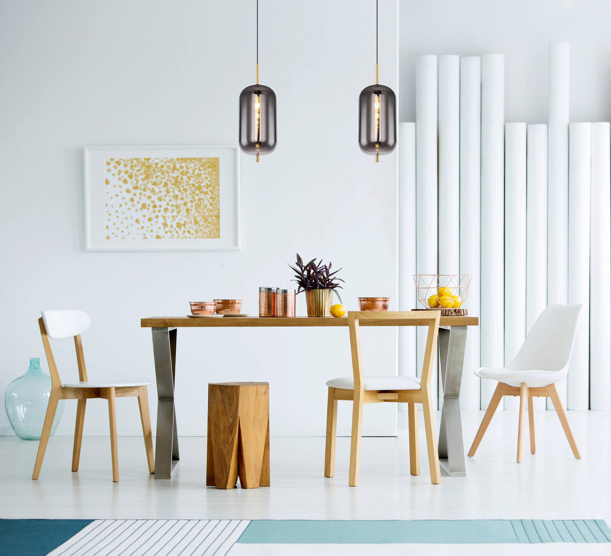Mise en ambiance au-dessus d'une table blanche, deux suspensions en verre fumé éclairées.