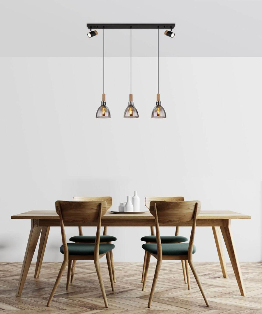 Mise en scène au-dessus d'une table en bois avec chaises vertes, suspension allumée.
