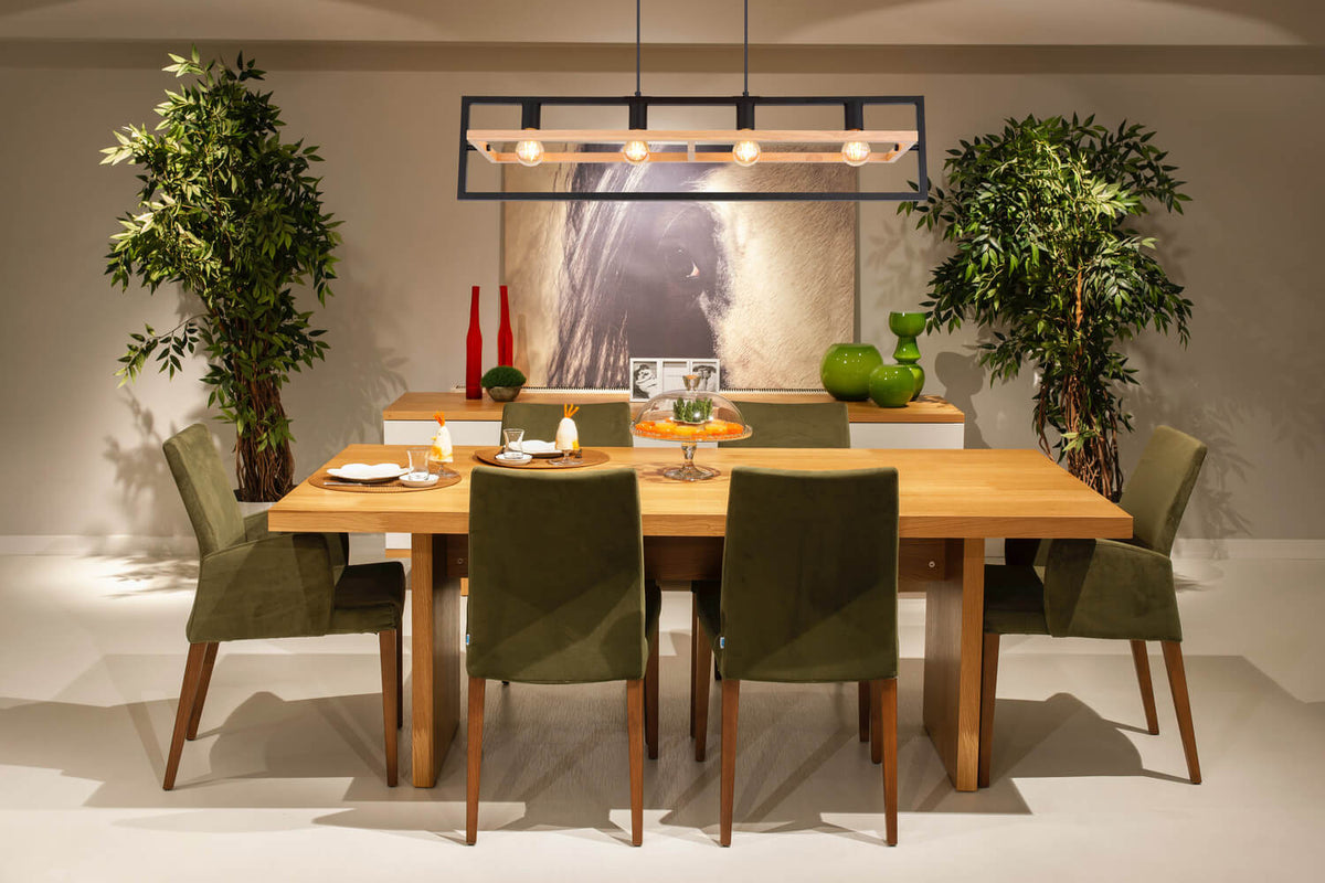 Mise en ambiance au-dessus d'une table de salle à manger en bois avec chaises vertes.
