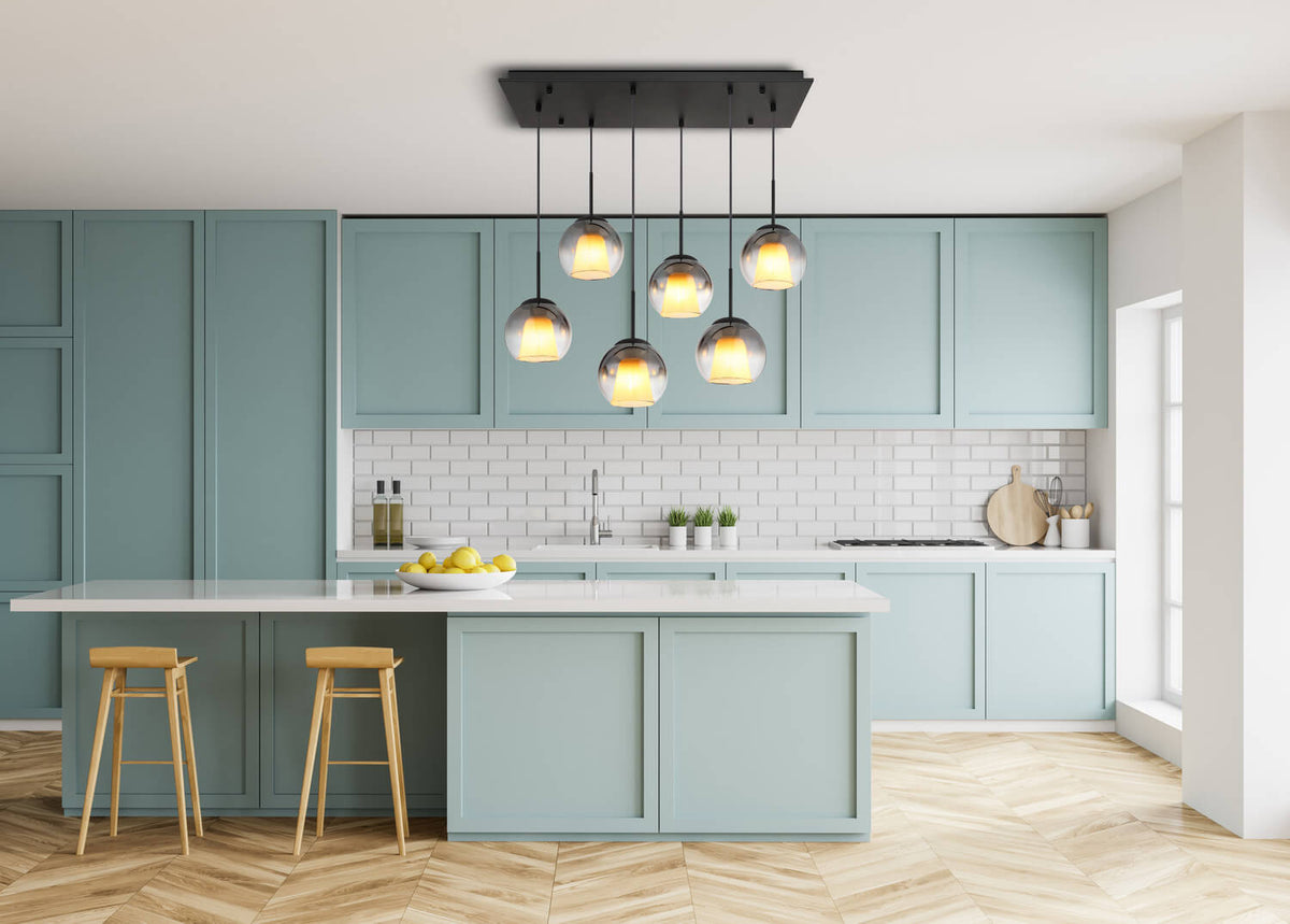 Mise en ambiance dans une cuisine bleu pâle, suspension allumée au-dessus de l'îlot.