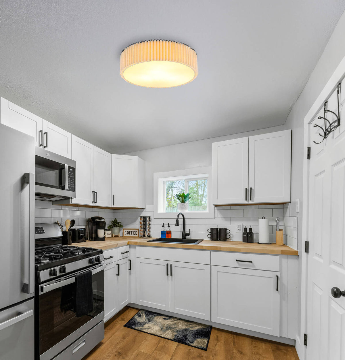 Plafonnier allumé installé au plafond d'une cuisine blanche et bois.
