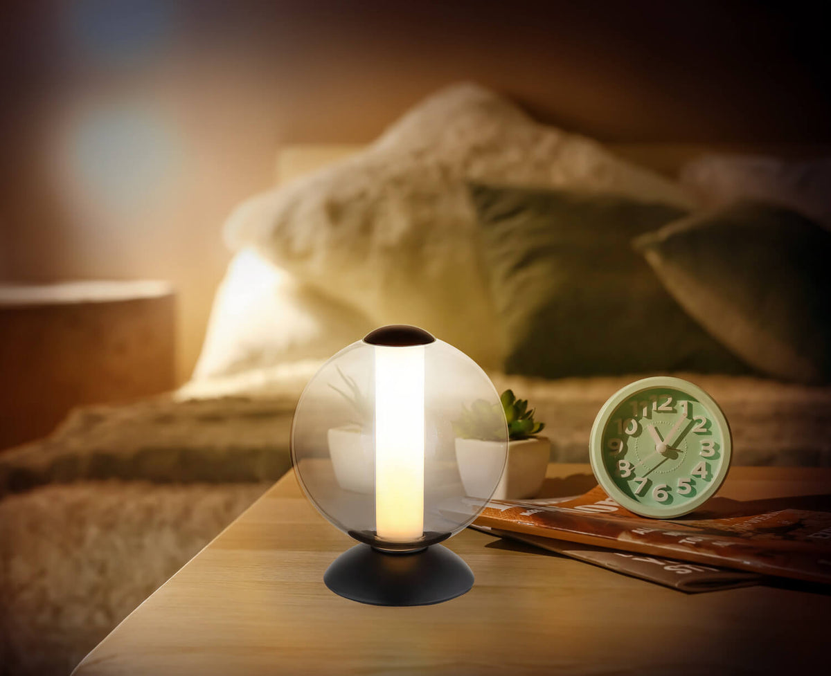 Mise en ambiance nocturne sur table de nuit, lampe allumée près d'un réveil vert