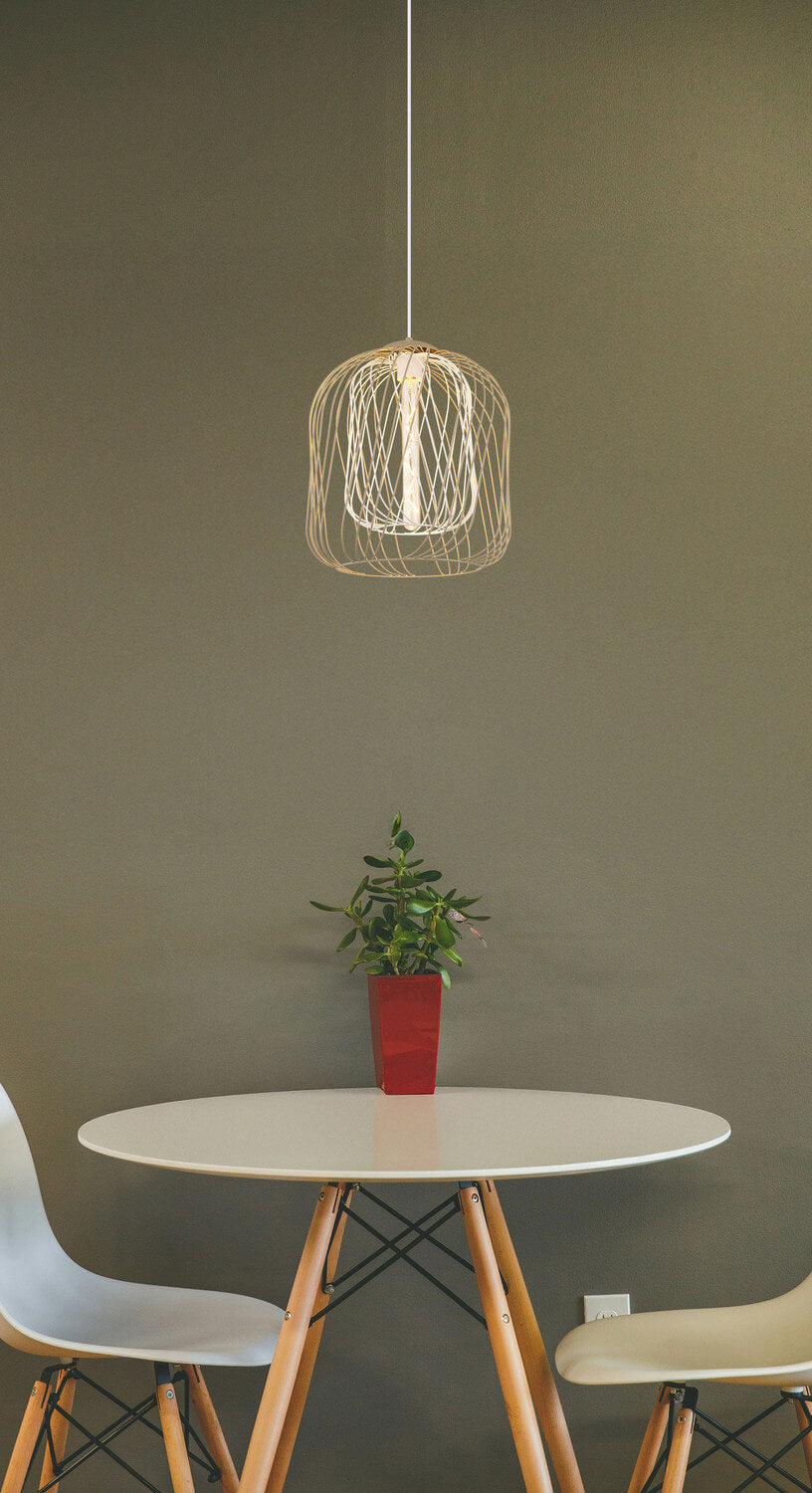 Mise en ambiance : suspension allumée au-dessus d'une table ronde avec plante verte