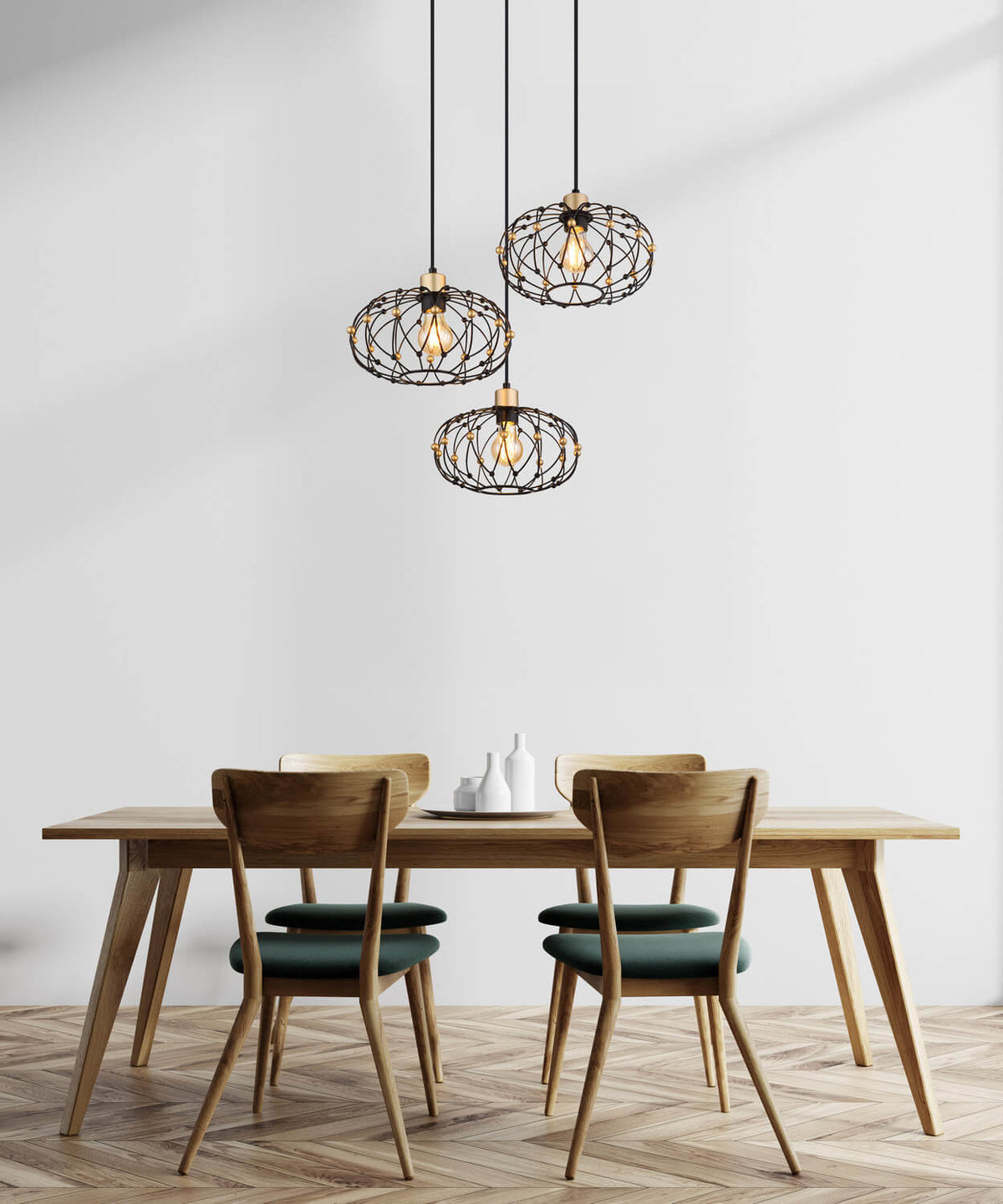 Mise en ambiance au-dessus d'une table à manger en bois clair, chaises vertes, suspension noire allumée.