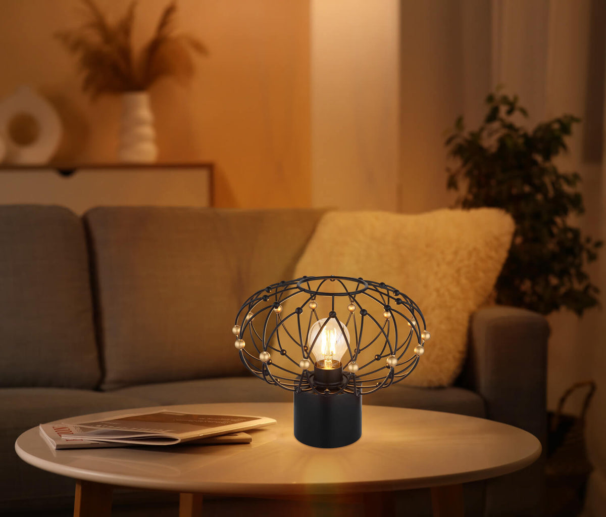 Mise en ambiance chaleureuse, lampe posée sur table basse devant un canapé et des coussins.