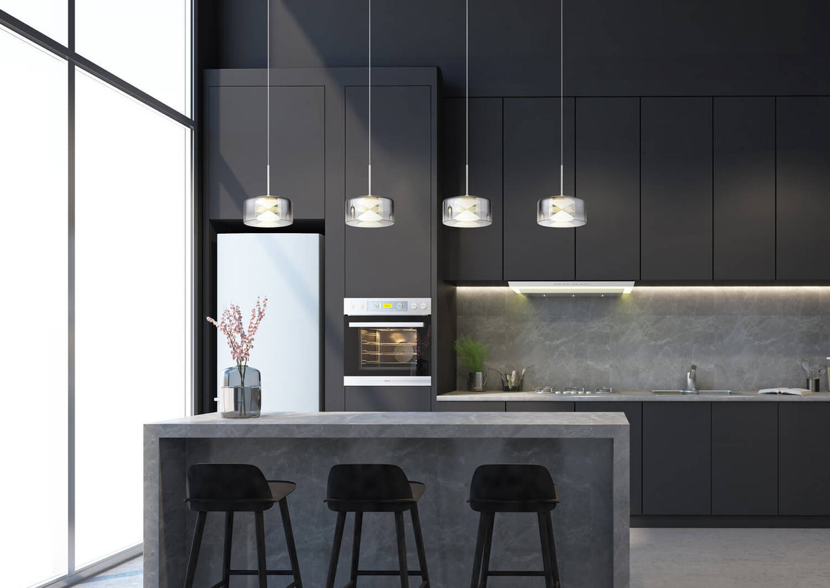 Ambiance cuisine moderne avec les quatre suspensions allumées au-dessus d'un îlot central.