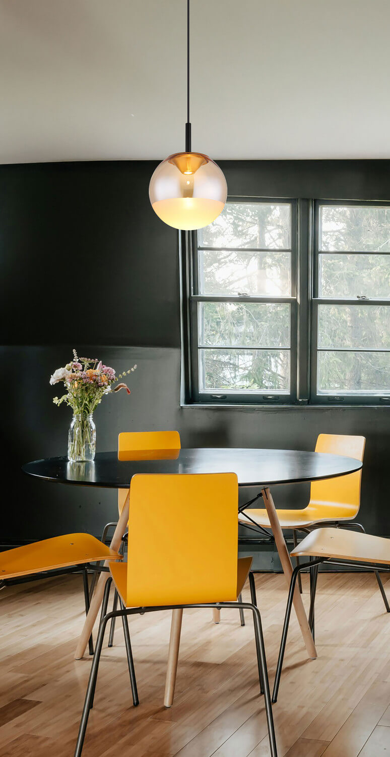 Mise en ambiance au-dessus d'une table ronde noire, chaises jaunes et mur sombre
