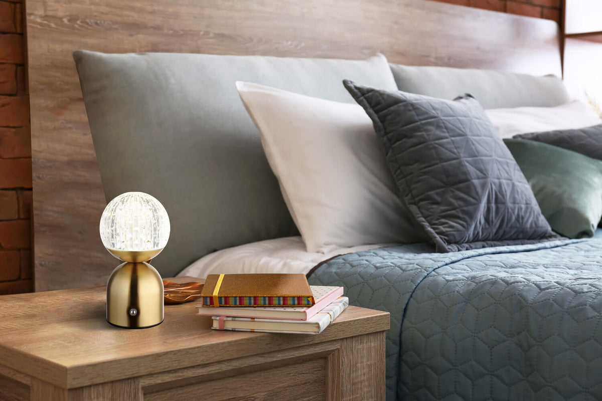 Mise en ambiance sur une table de chevet en bois avec livres et coussins