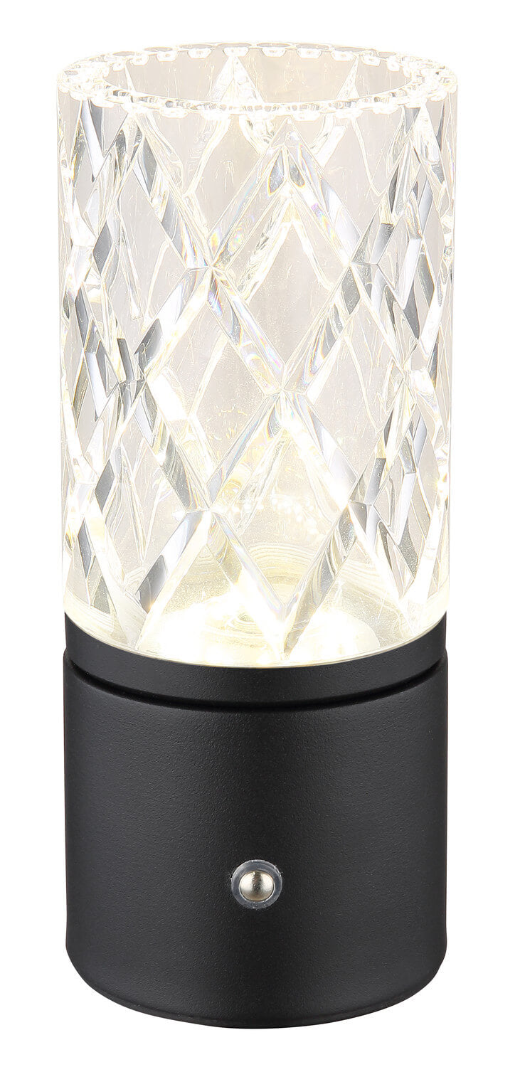 Vue rapprochée du luminaire allumé, abat-jour à facettes cristallines, base noire et petit interrupteur chromé.