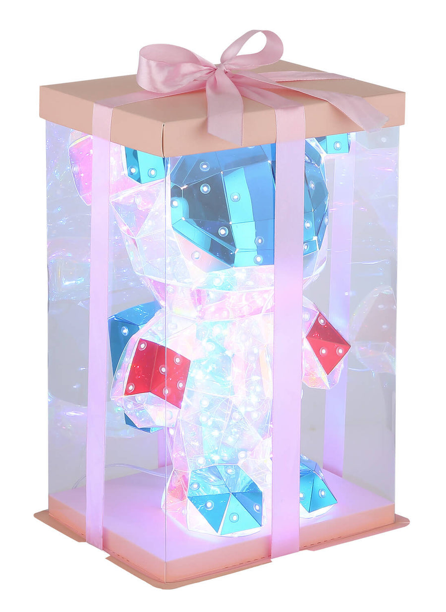 Vue de trois quarts du luminaire emballé dans son présentoir transparent avec ruban rose