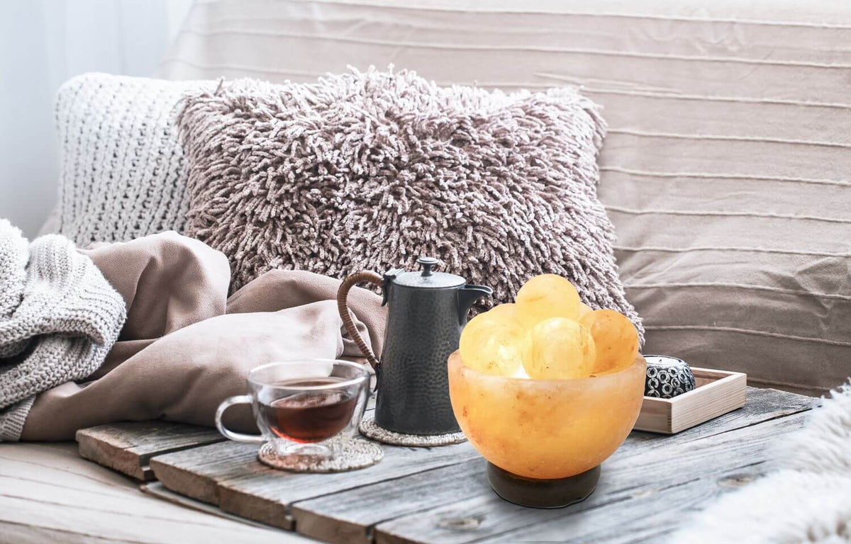 Mise en ambiance de la lampe posée sur table en bois, près d'une tasse de thé