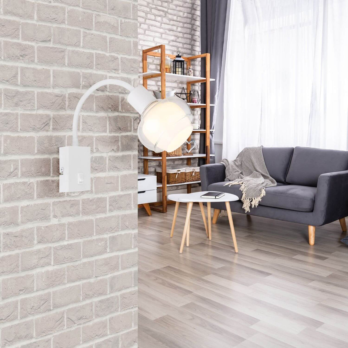 Applique blanche allumée sur mur de briques, près d'un canapé gris