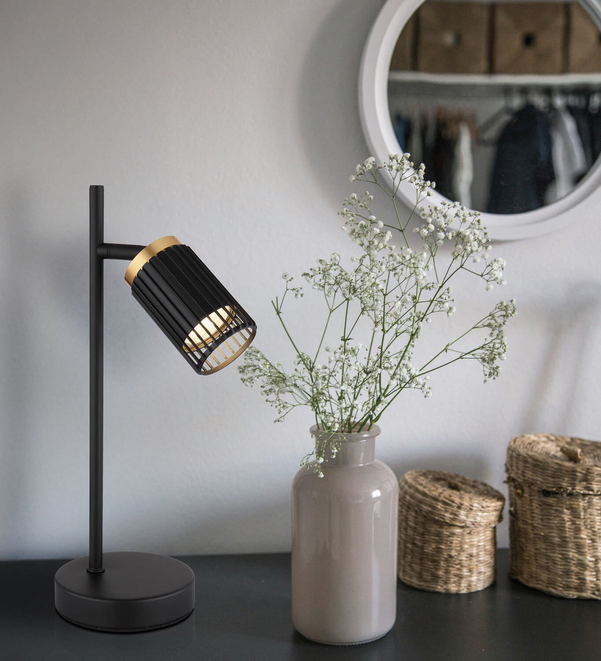 Mise en ambiance sur meuble noir, vase de gypsophiles et miroir rond au fond