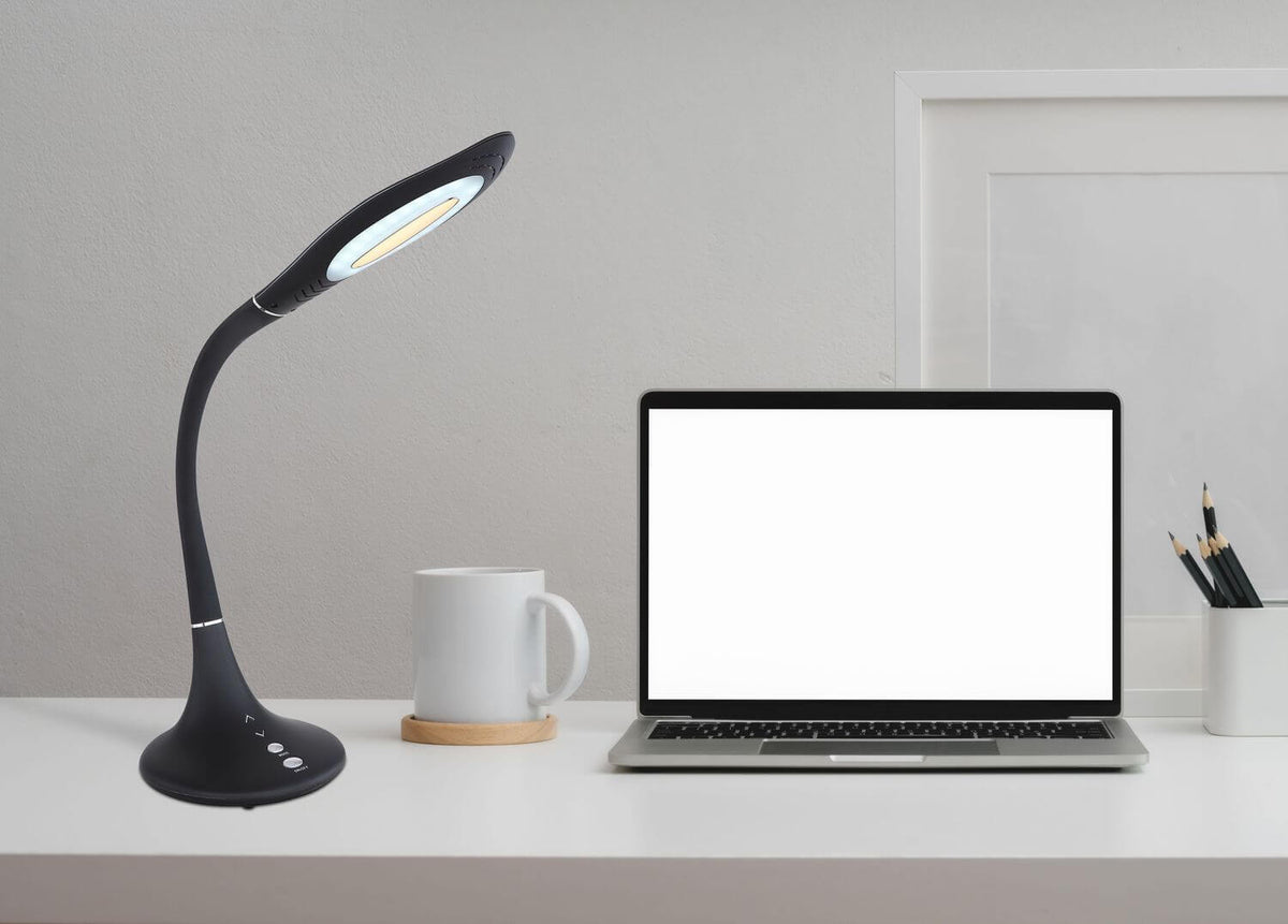 Lampe allumée posée sur un bureau blanc près d'un ordinateur portable
