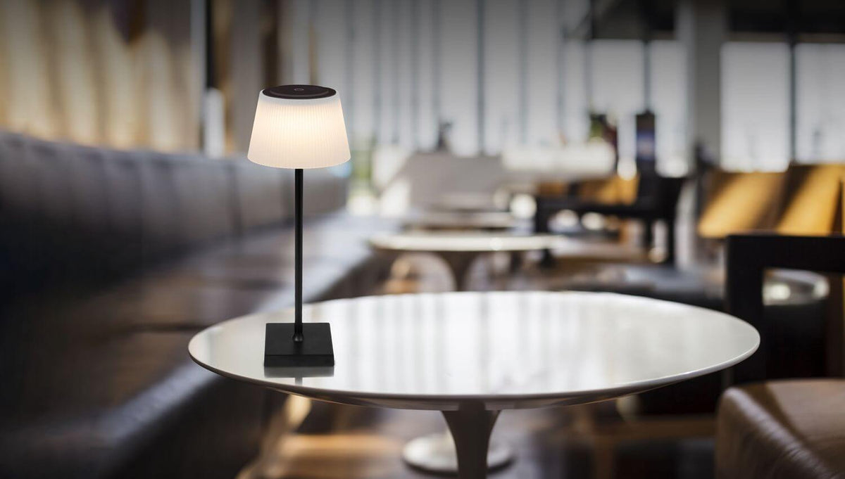 Lampe ivoire sur table ronde dans une ambiance de café chaleureuse et floue