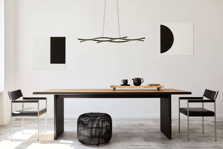 Luminaire suspendu au-dessus d'une table à manger dans un intérieur contemporain noir et blanc.