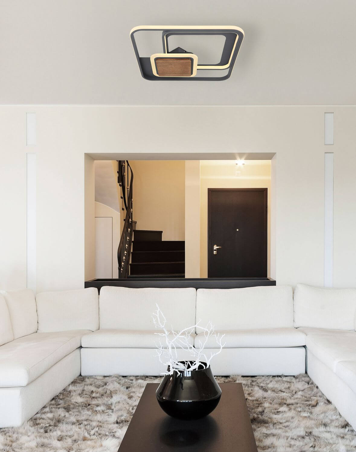 Mise en ambiance du plafonnier dans un salon contemporain au-dessus d'un canapé blanc.