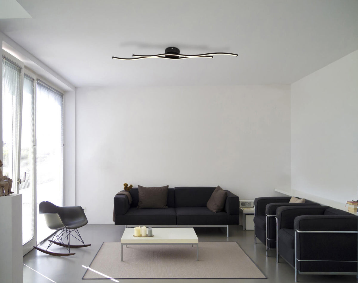Mise en ambiance dans un salon moderne avec plafonnier noir fixé au plafond au-dessus du canapé.