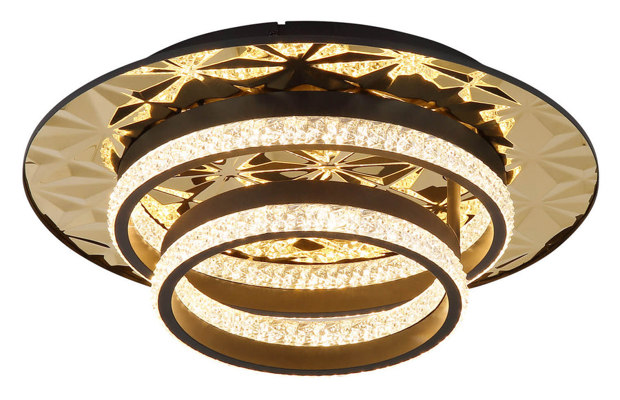 Vue en contre-plongée du luminaire, anneaux superposés et éclairage chaleureux sur fond blanc.